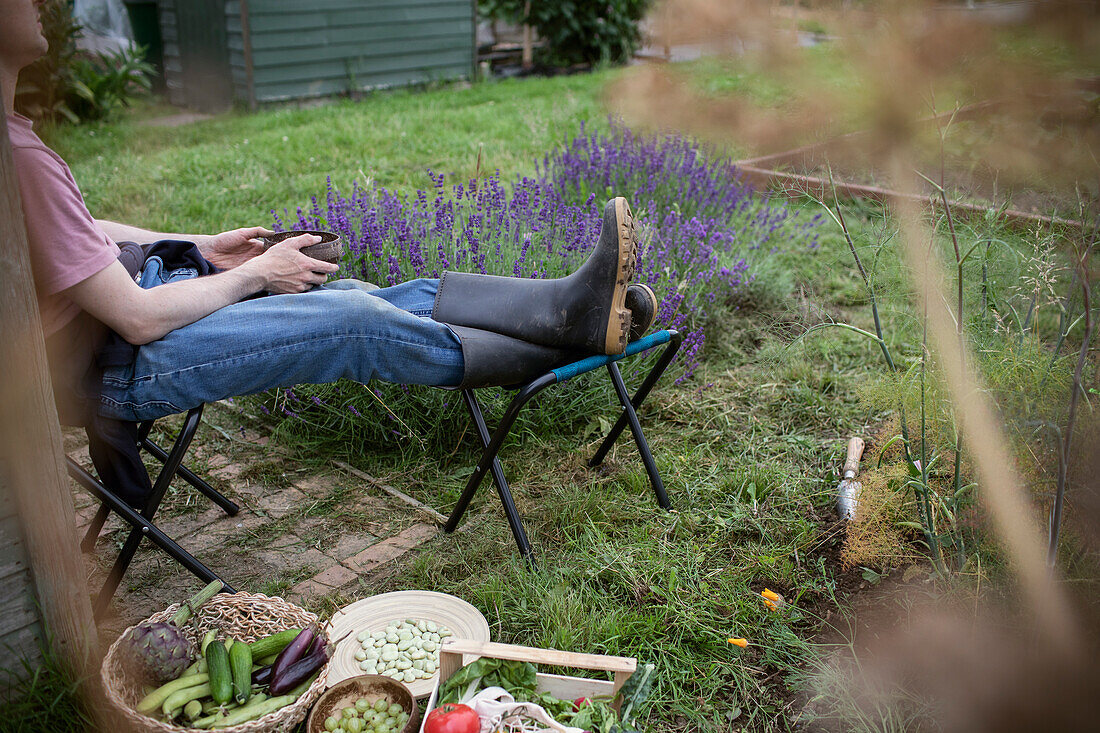 Man relaxing in garden with harvested vegetables