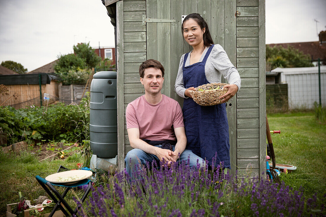 Smiling couple with basket of vegetables in garden