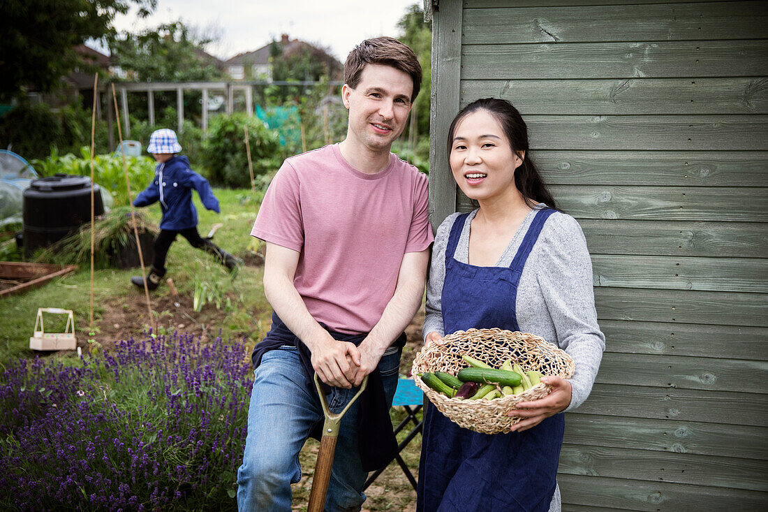 Happy couple with harvested vegetables in garden