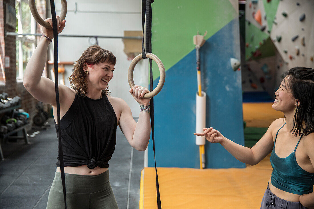 Happy female rock climbers training at gymnastics rings