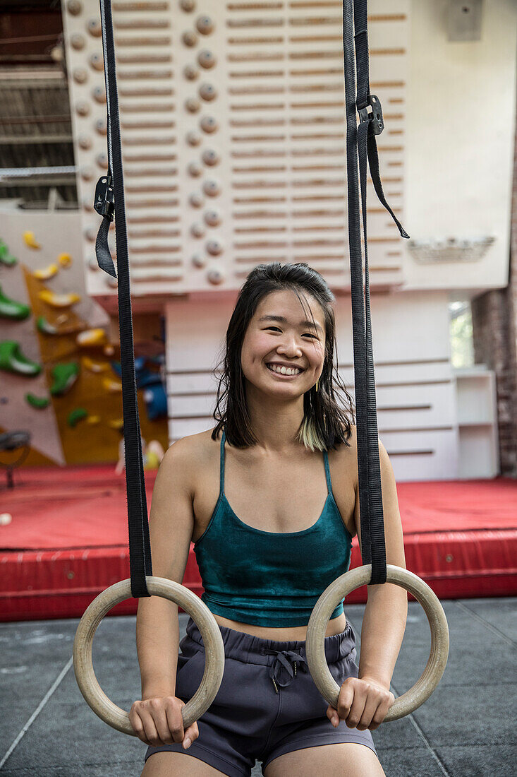 Happy female rock climber training at climbing gym