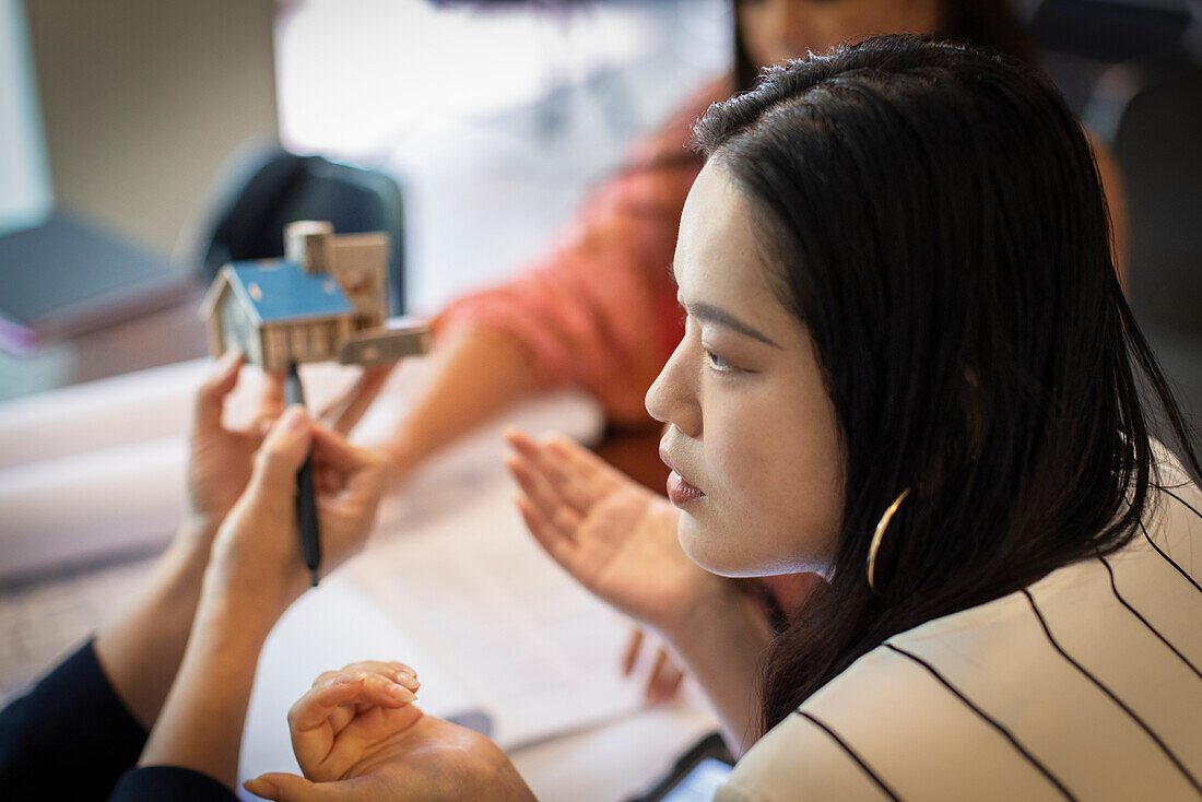 Female architect discussing house model with colleagues