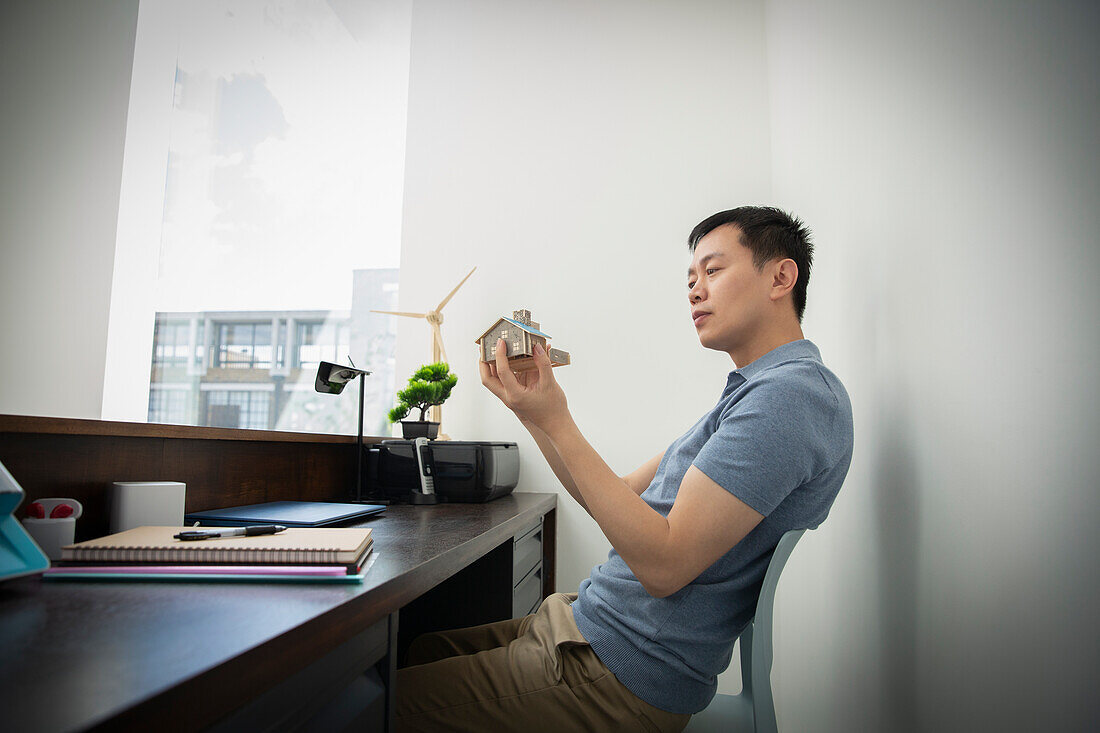 Male engineer looking at house model at office desk