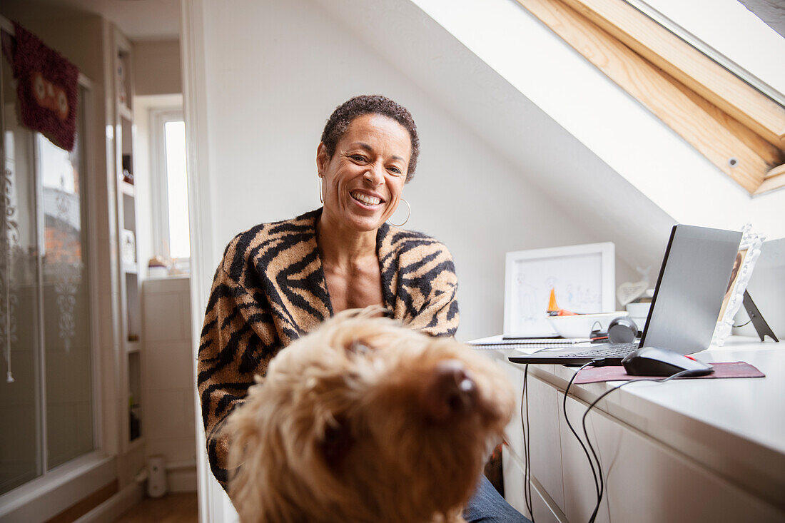 Portrait happy woman with dog at desk in home office