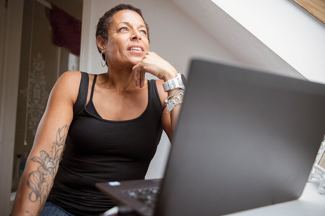 Thoughtful mature woman working from home at laptop