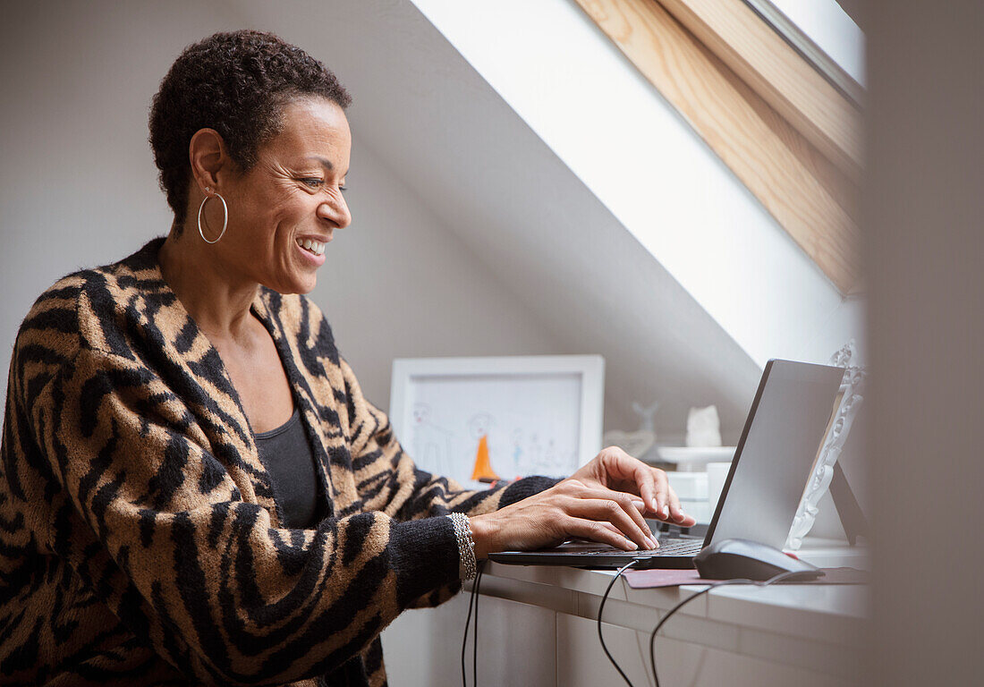 Smiling mature woman working from home at laptop
