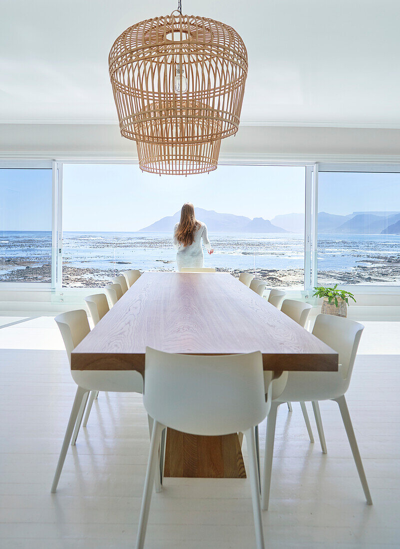Woman standing at open dining room door with ocean view