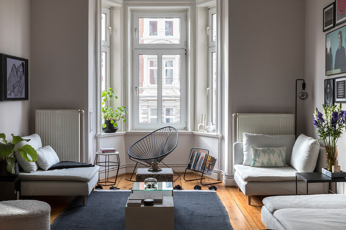 Verschiedene Sitzmöbel im Altbau-Wohnzimmer mit Holzdielenboden und Erkerbereich