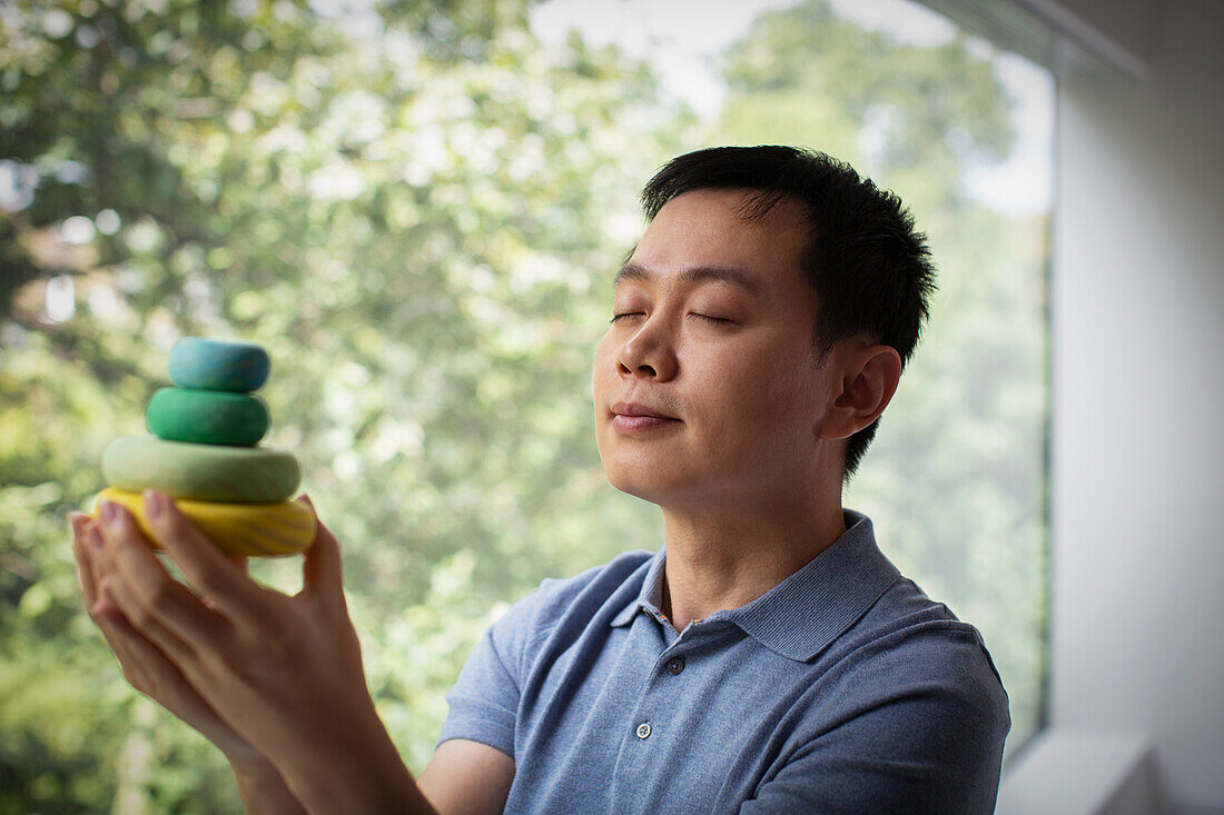 Man holding stacked wooden circles at window