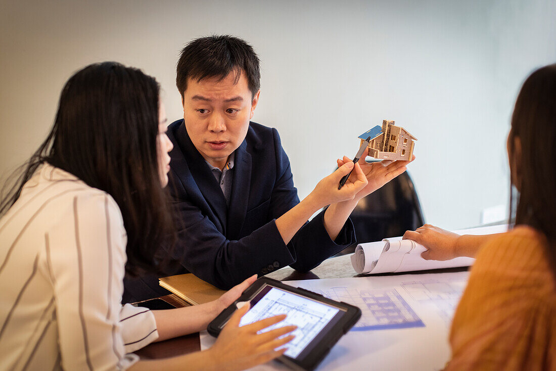 Architects looking at house model in conference room meeting