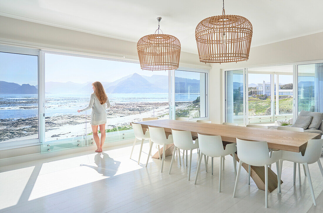 Woman enjoying ocean view from sunny modern dining room
