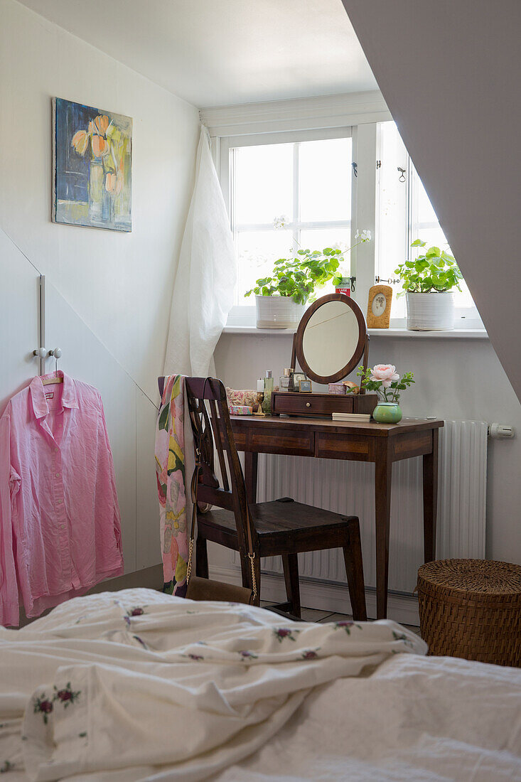 Antiker Schminktisch vor Fenster mit Geranien im Schlafzimmer