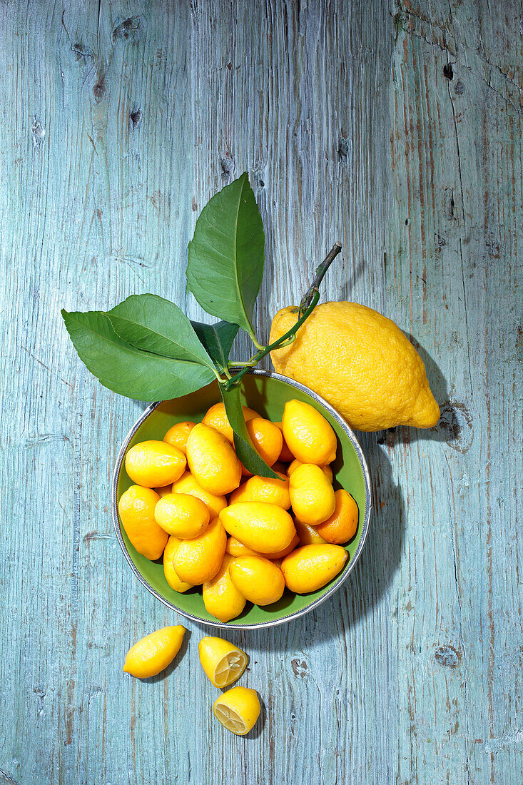 Snack lemons in a bowl, next to it lemon with leaves