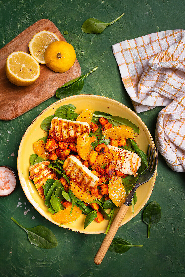 Salad with spinach, roasted pumpkin, orange, grilled halloumi, and chili