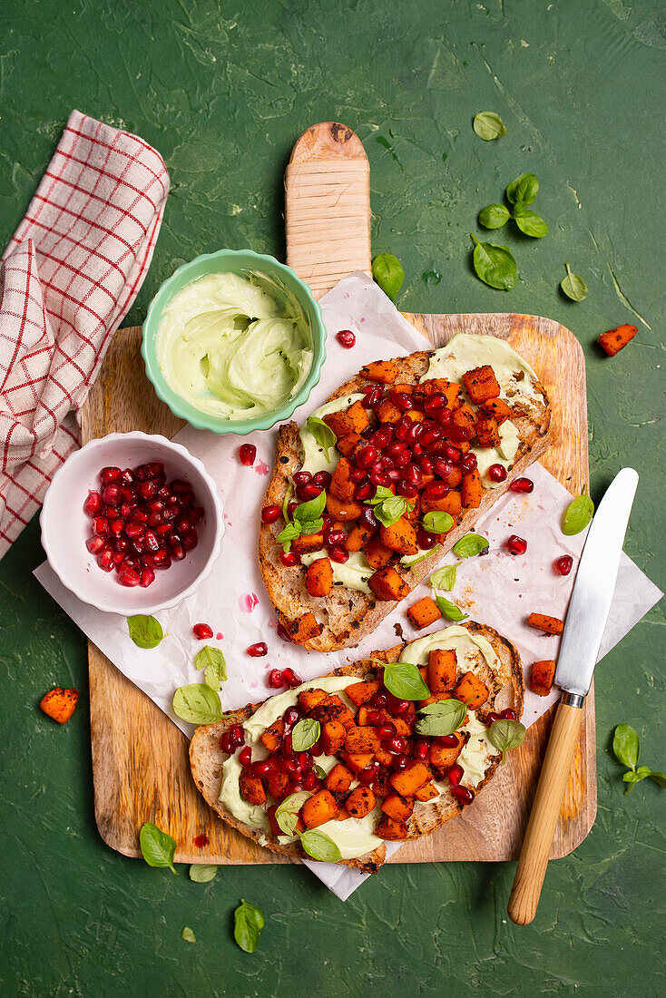 Brotscheiben mit Joghurt-Avocado-Paste, frittiertem Kürbis, Granatapfelkernen und Basilikum