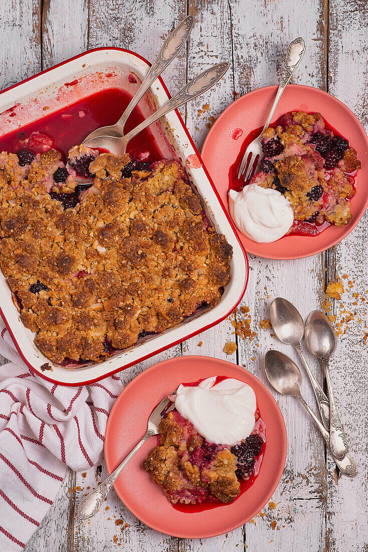 Strawberry and blackberry cobbler with streusel topping, served with yogurt