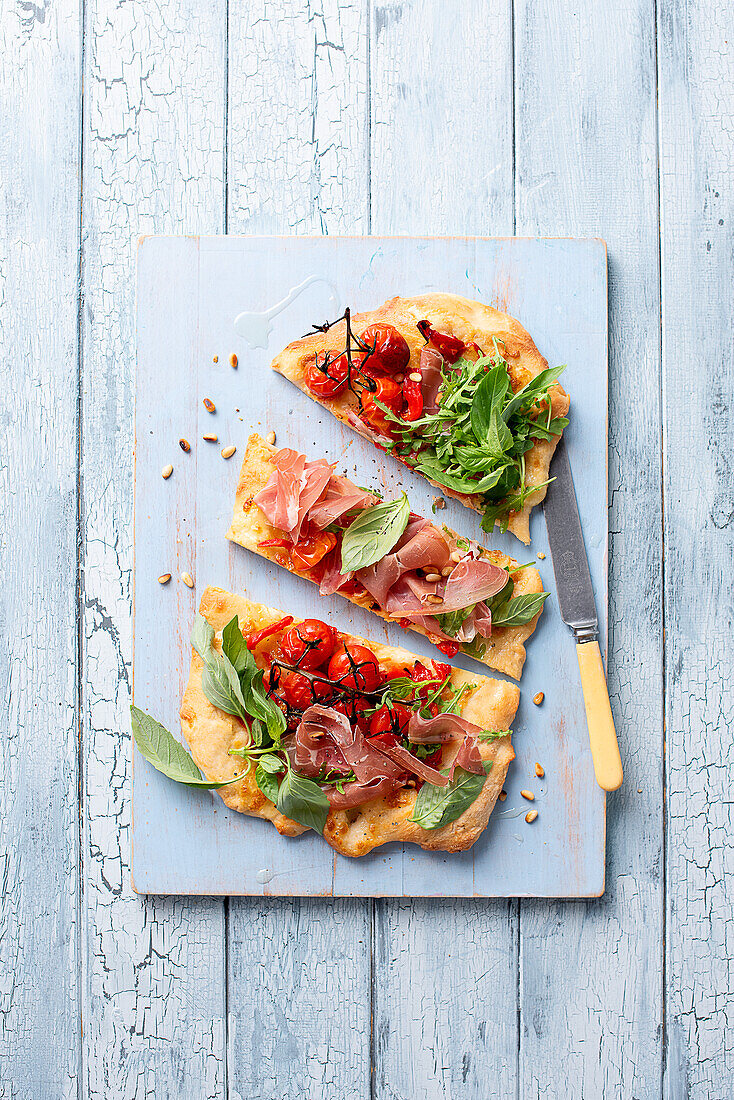 Pinsa mit gerösteten Paprika, Tomaten, Parmaschinken, Basilikum und Rucola