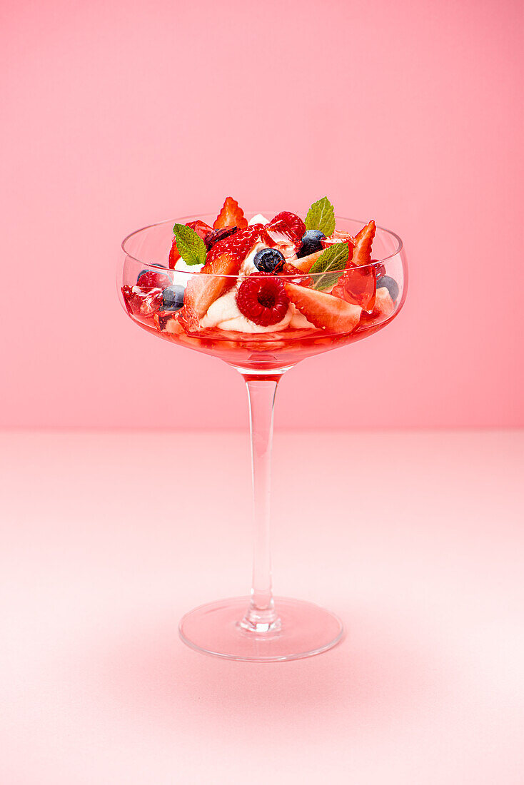 Strawberry jelly with cream and fruit in a stem glass