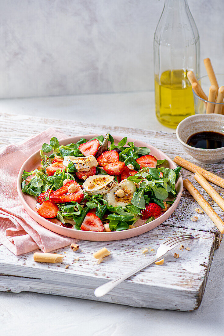 Grüner Salat mit Erdbeeren, gegrilltem Ziegenkäse, Haselnüssen und Balsamico-Vinaigrette