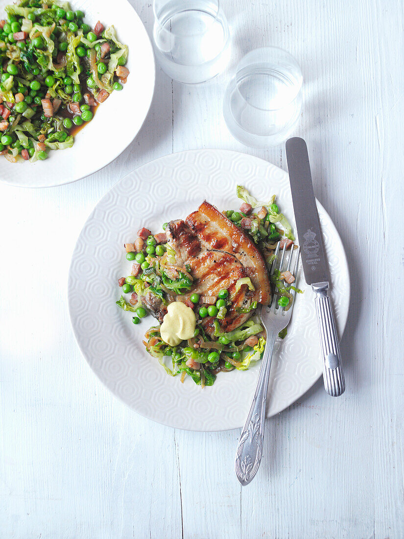 Gegrillte Schweinekoteletts mit geschmortem Salat und Erbsen