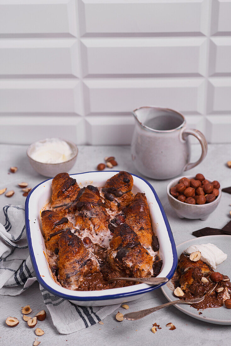 Gebackener Croissant-Pudding mit Schokoladensauce und Haselnüssen