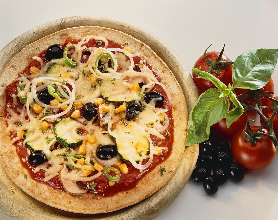 Pizza with vegetable topping and cheese on wooden board
