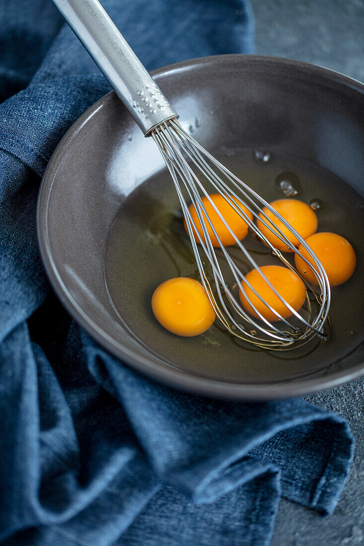 Rohe Eier mit Schneebesen in einer Schüssel