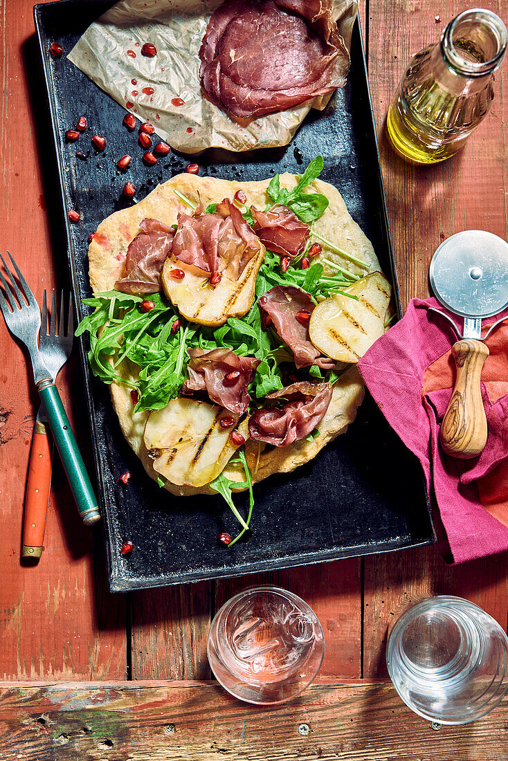 Pinsa with bresaola, ruccola, pomegranate and grilled pears