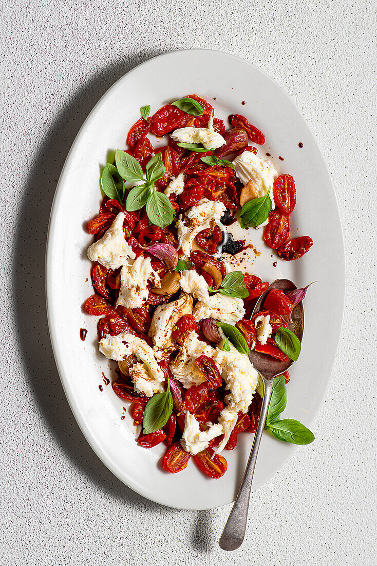 Salad from roasted cherry tomatoes with roasted garlic, mozzarella, basil and balsamic vinegar