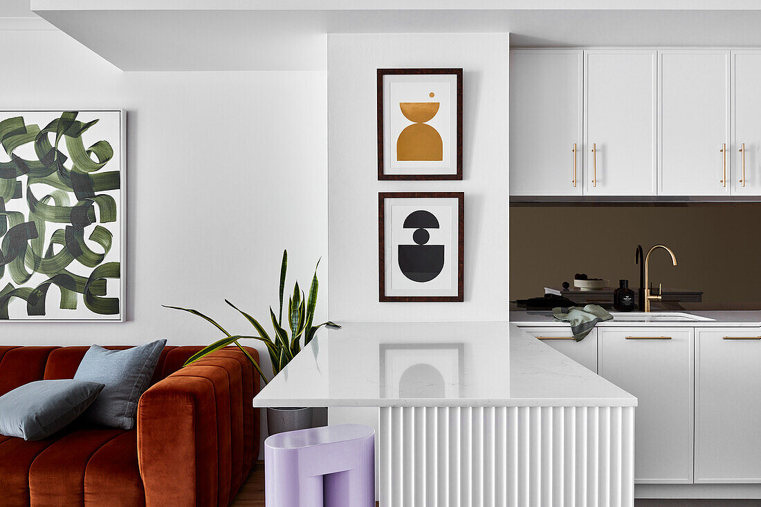 A living room-cum-kitchen with fluted woodwork, brushed gold fittings and marble worktops