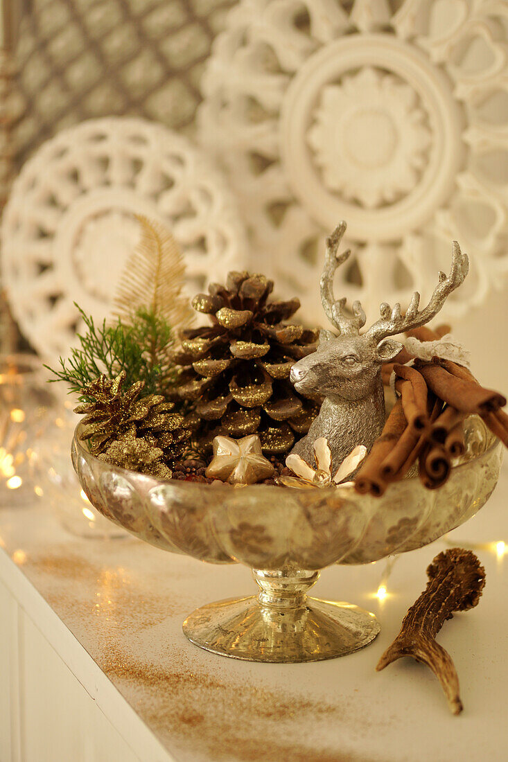 Schale mit goldenen Kiefernzapfen, Hirsch und Zimt als Weihnachtsdeko