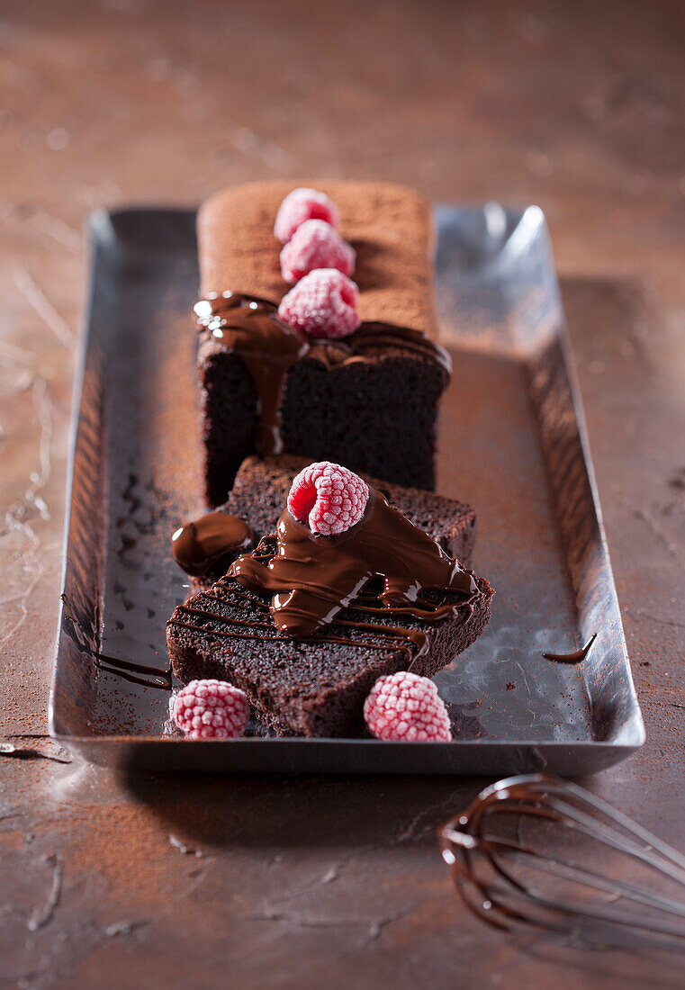 Chocolate cake with chocolate sauce and frozen raspberries