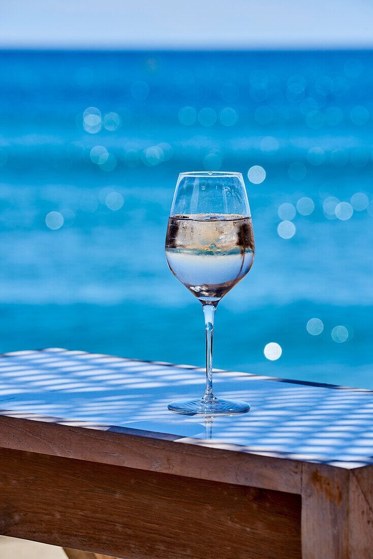 A glass of white wine on a table by the sea
