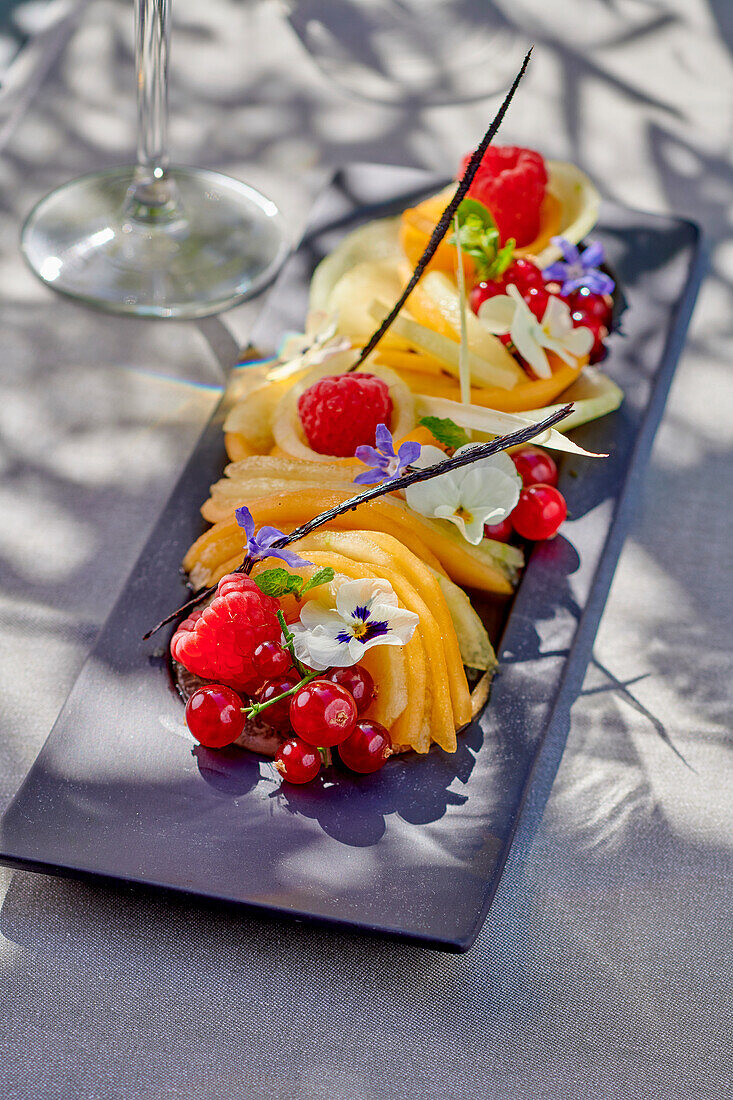 Honigmelone mit roten Beeren, Blüten und Vanilleschoten