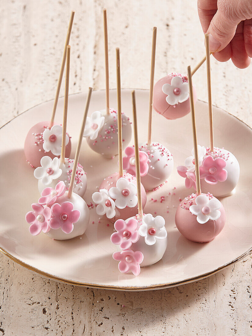Süße rosa-weiße Cake Pops mit Zuckerblüten dekoriert