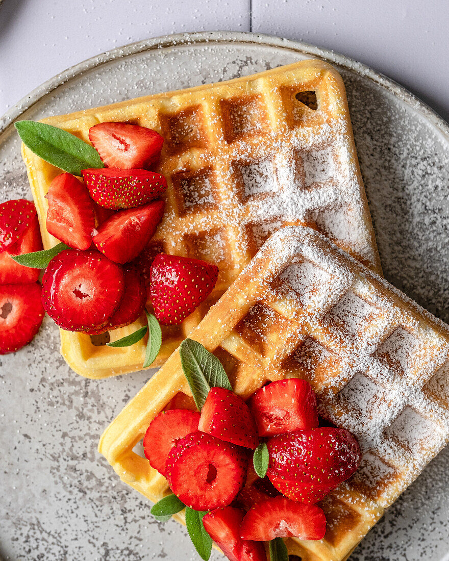 Waffles with strawberries, sage and powdered sugar