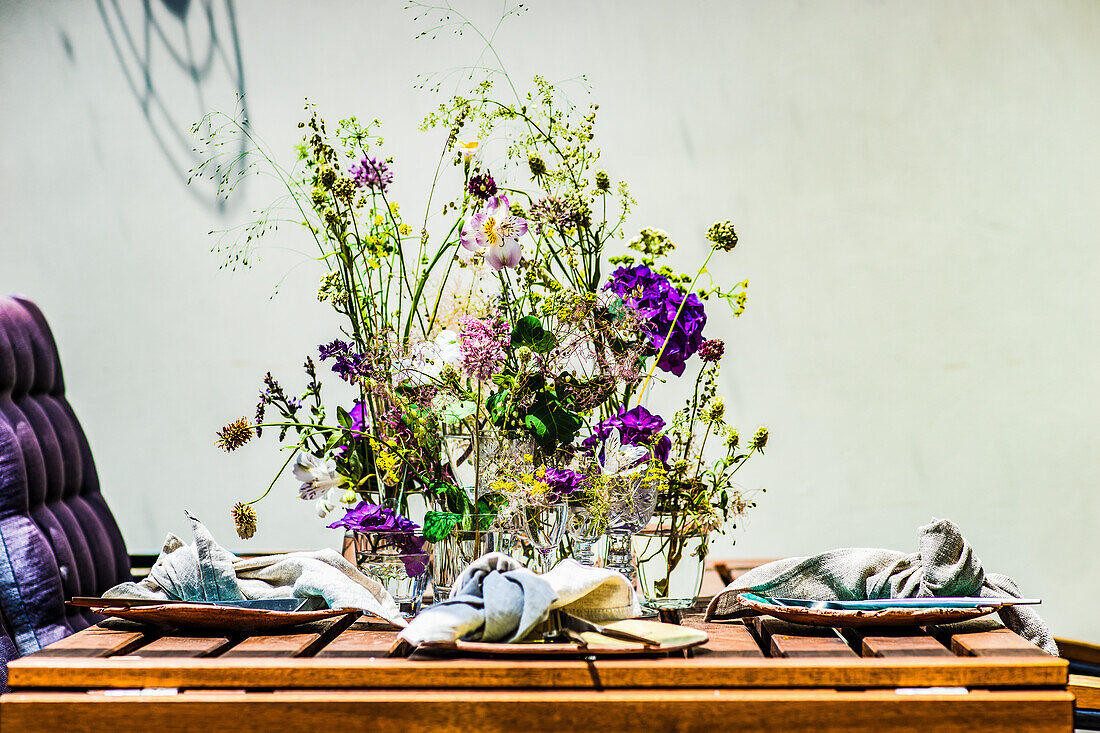 A table laid on a summer terrace decorated with wild flowers