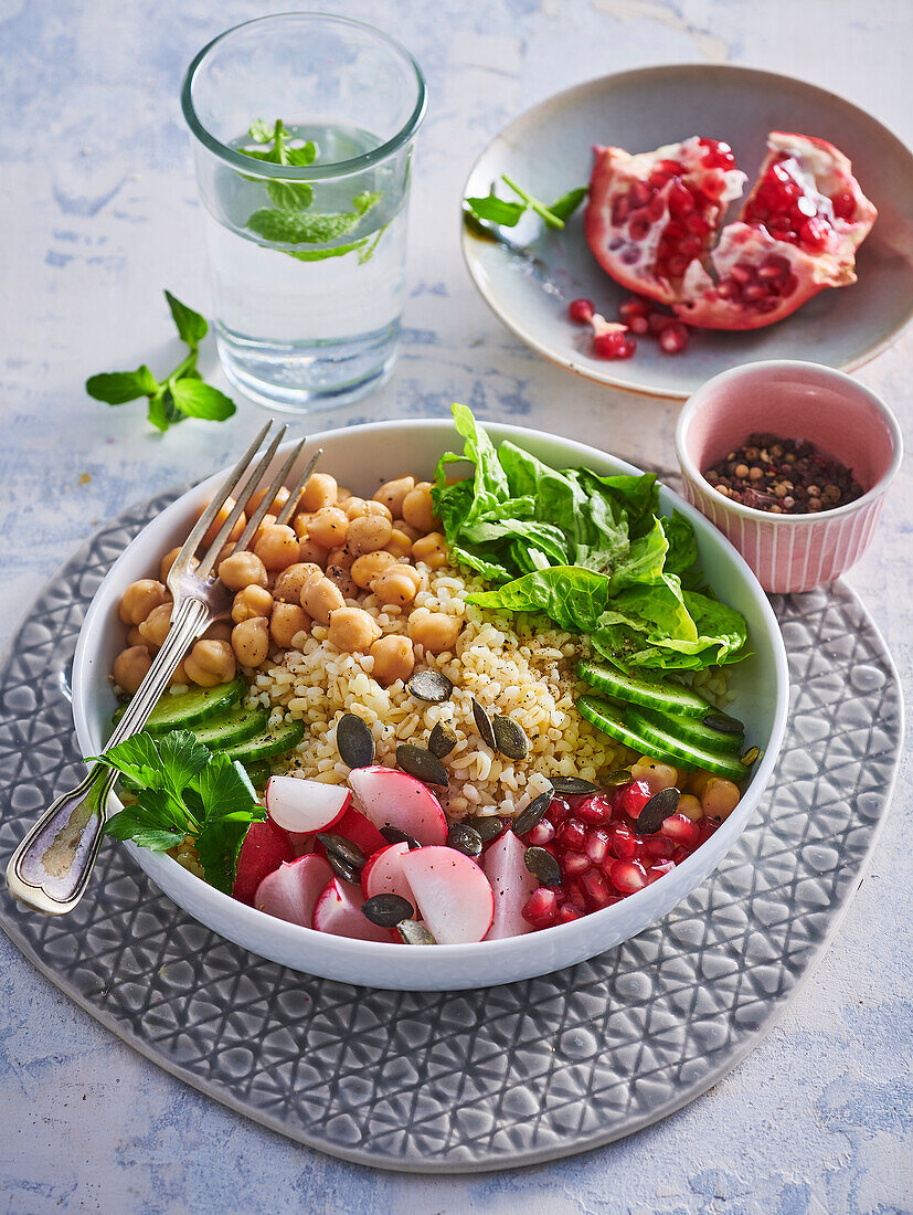 Bowl mit Bulgur, Kichererbsen, Radieschen und Granatapfelkernen