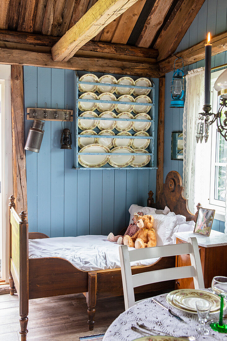 Tellerboard an blauer Wand über Kinderbett in einem Cottage