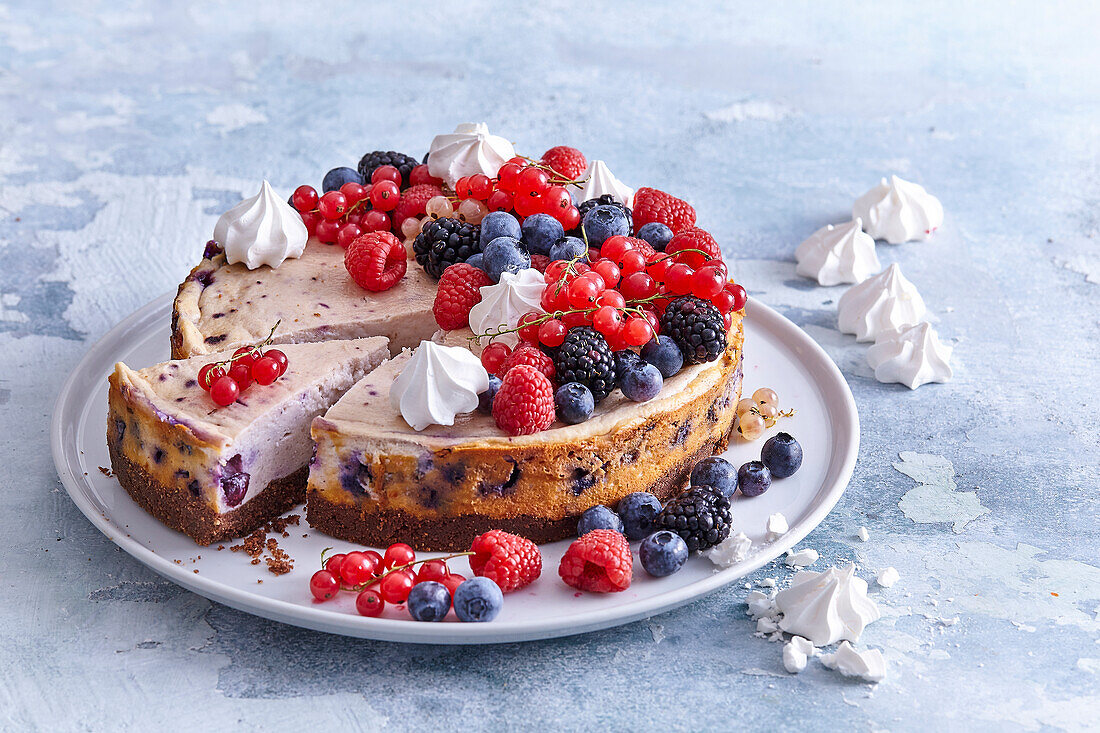 Heidelbeer-Käsekuchen dekoriert mit Sommerbeeren und Baisertupfen