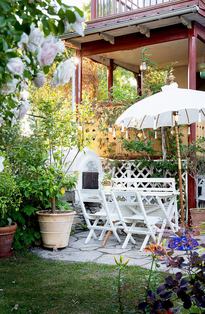 Dining area on a terrace with umbrella and outdoor oven