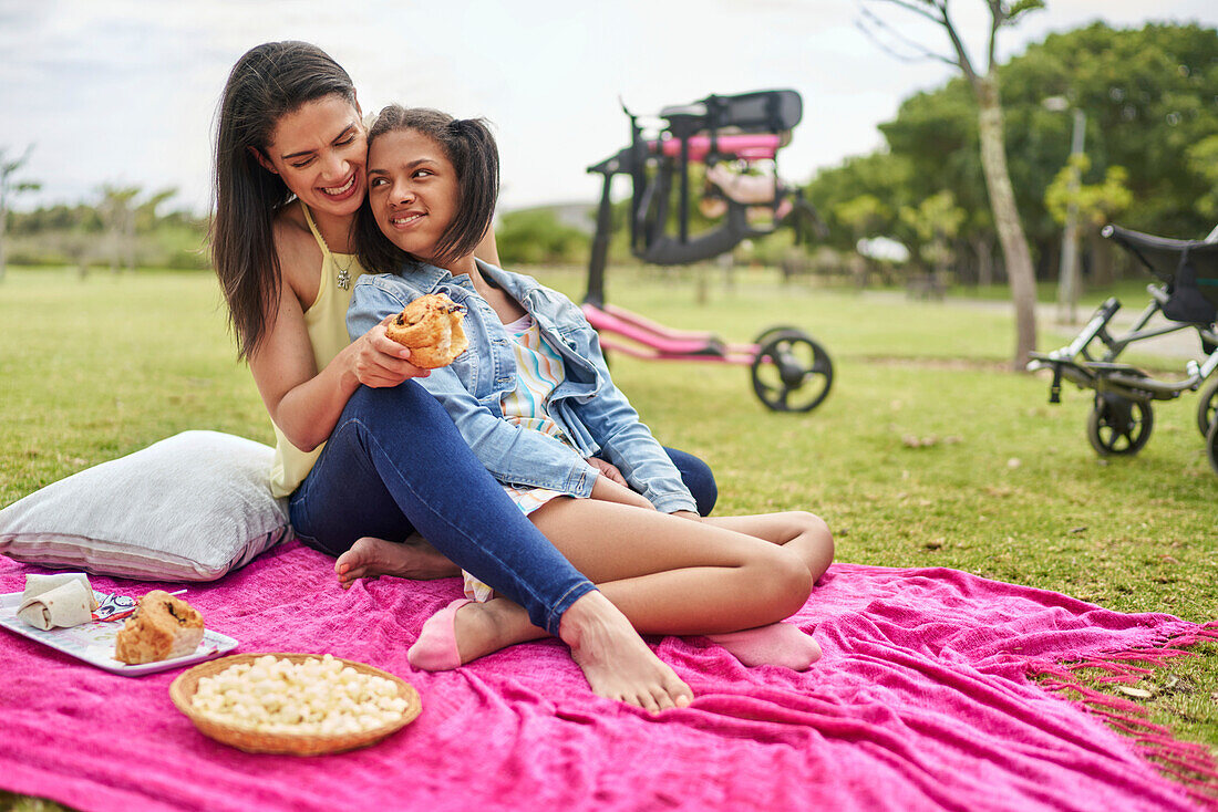 Happy mum and disabled daughter enjoying picnic on blanket