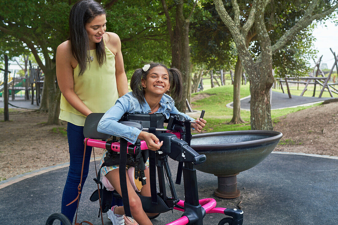 Mother and happy disabled daughter in rollator at park