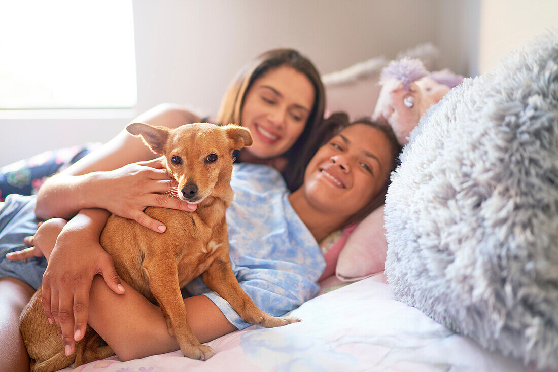 Happy mother, disabled daughter and dog cuddling on bed