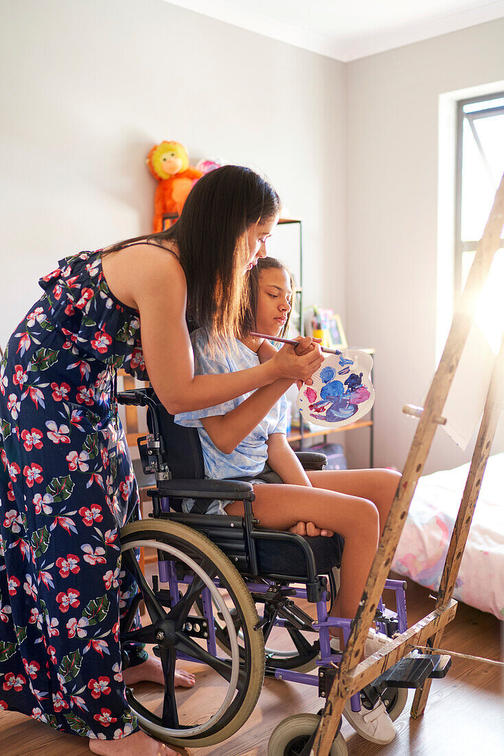 Mother and disabled daughter in wheelchair painting at home