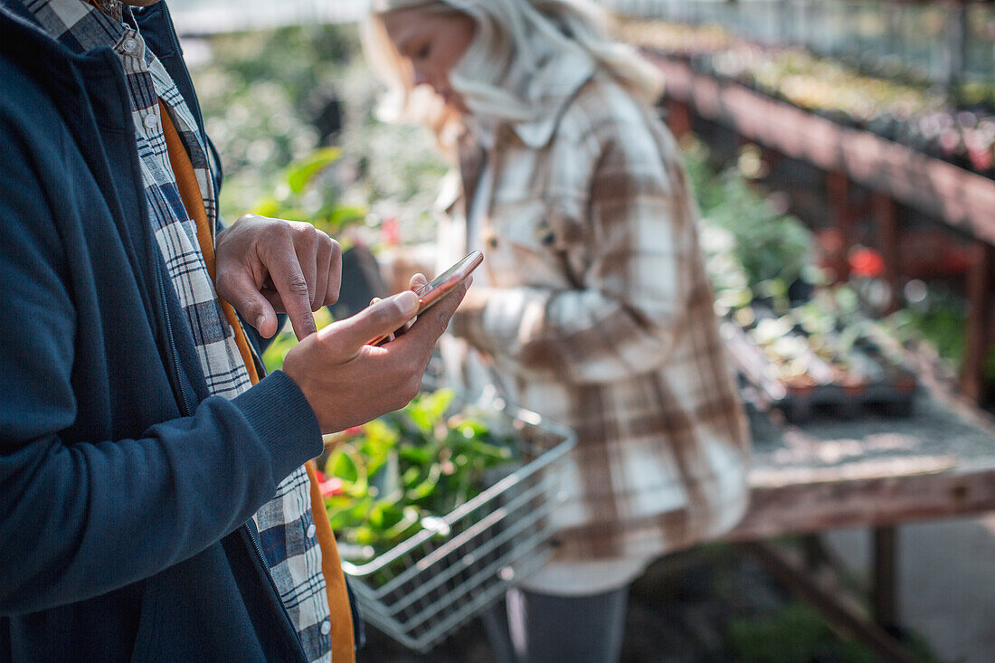 Customer with smart phone shopping in plant nursery