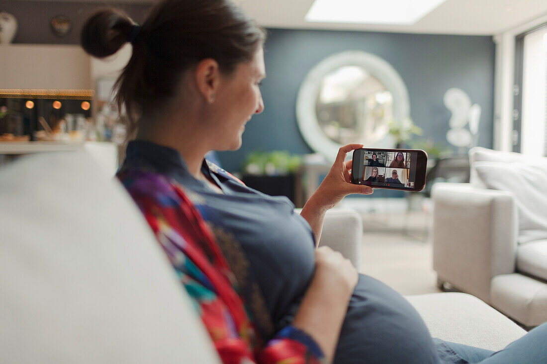 Pregnant woman video chatting with friends on smart phone