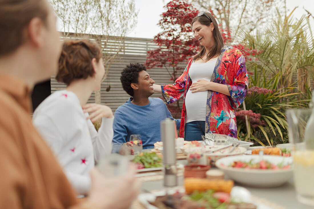 Pregnant couple enjoying lunch with friends at patio table