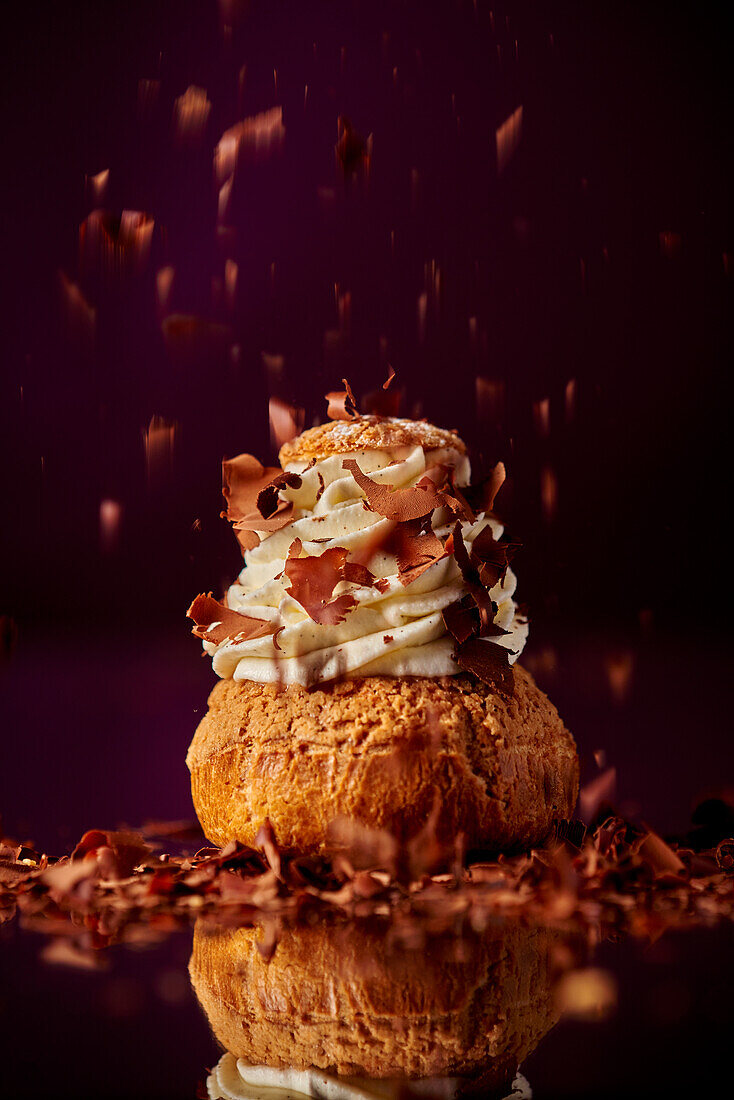 Chocolate cream puff with cream and chocolate shavings