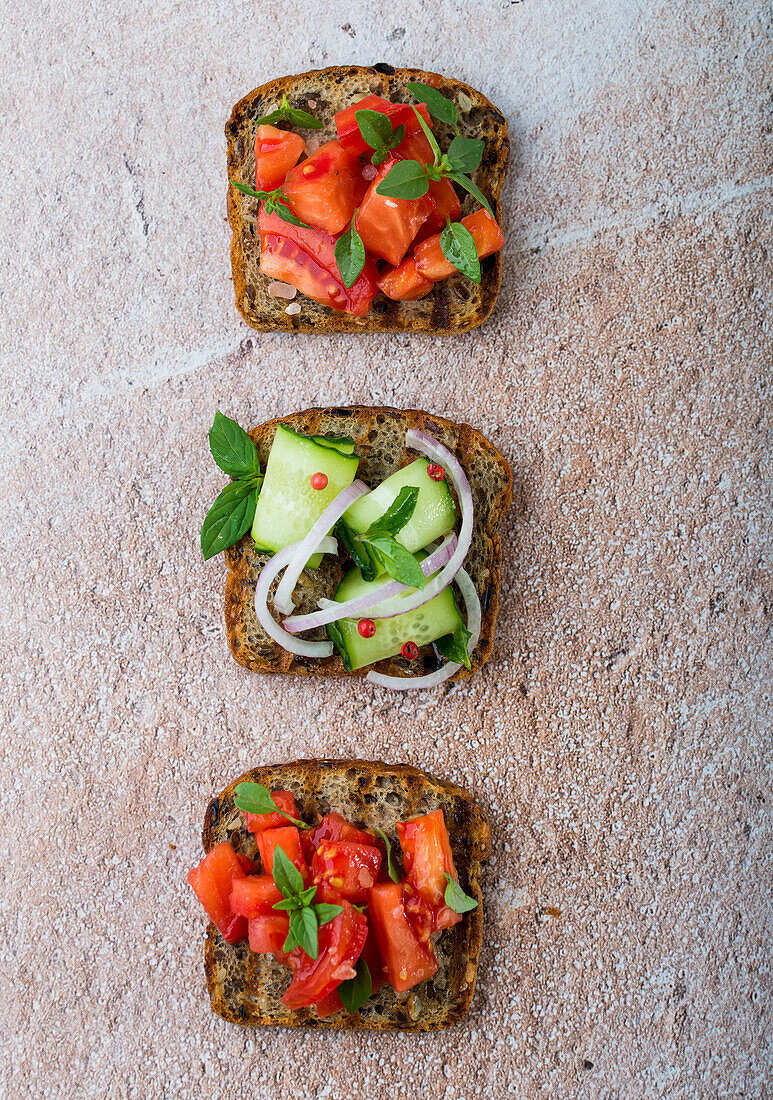 Gegrillte Brotscheiben mit frischen Tomaten, Gurken und roten Zwiebeln